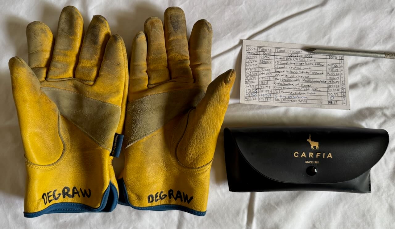 Leather gloves, a sunglasses case, and a 3x5 index vehicle maintenance log.