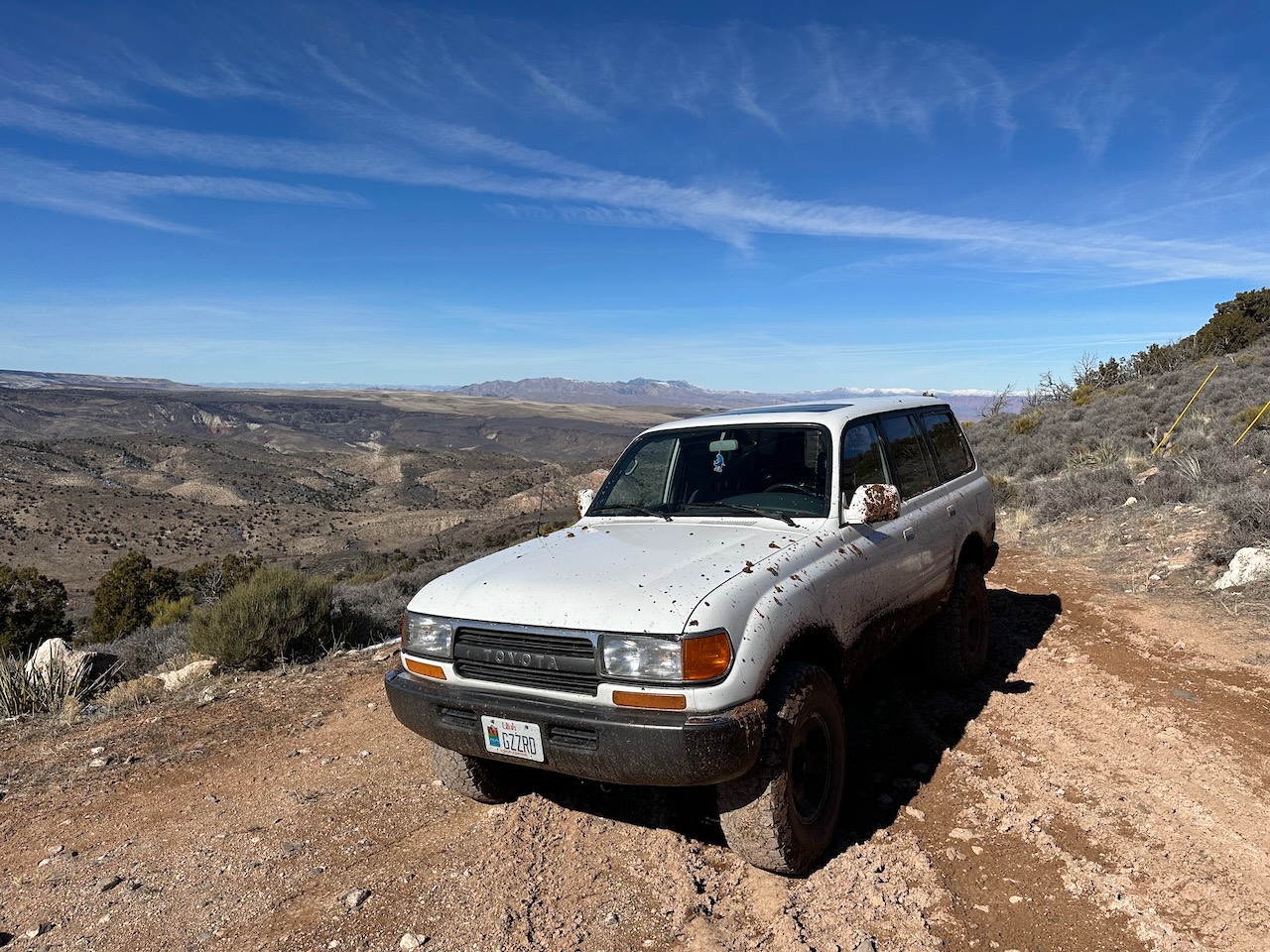 My 1994 Toyota Land Cruiser caked in mud atop a majestic peak with an epic blue sky in the background.